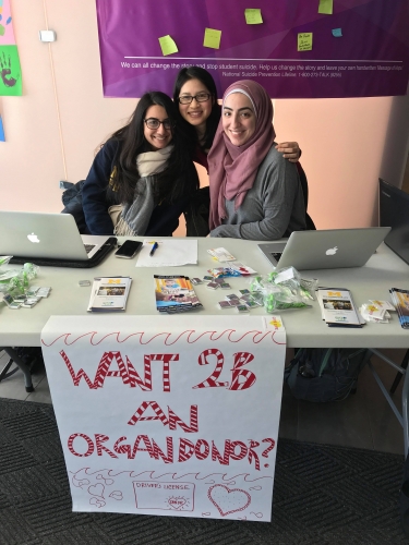 Girls posing behind "Want to be an organ donor?" sign.