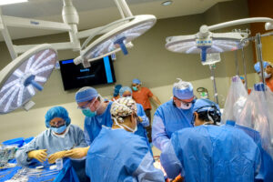 People in scrubs standing over an operating table