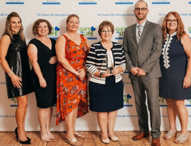 6 people dressed up, one holding an award