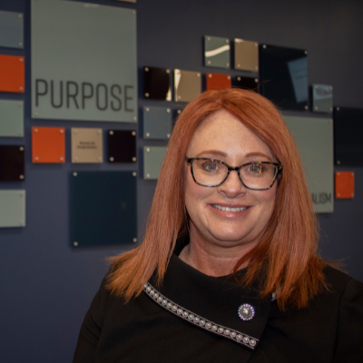 Woman posed in front of an indoor mission/vision display