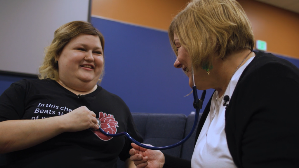 Woman uses stethoscope to listen to heart beat in another woman