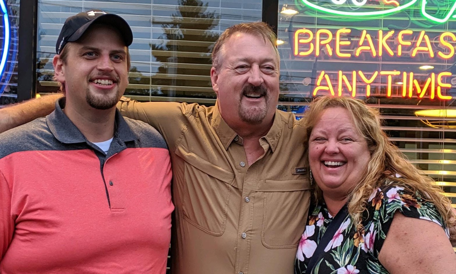 Two men and a woman with arms around each other