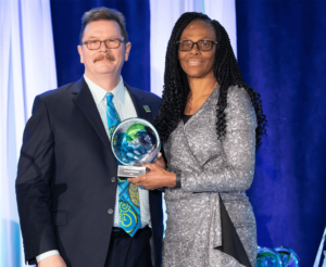 Man presenting blue and green glass award to woman