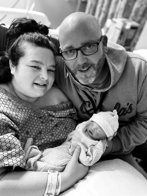 black and white photo of a newborn baby with her parents in the hospital shortly after delivery