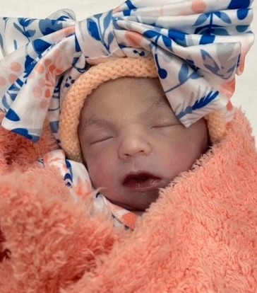 Newborn baby wrapped in orange towel with headband