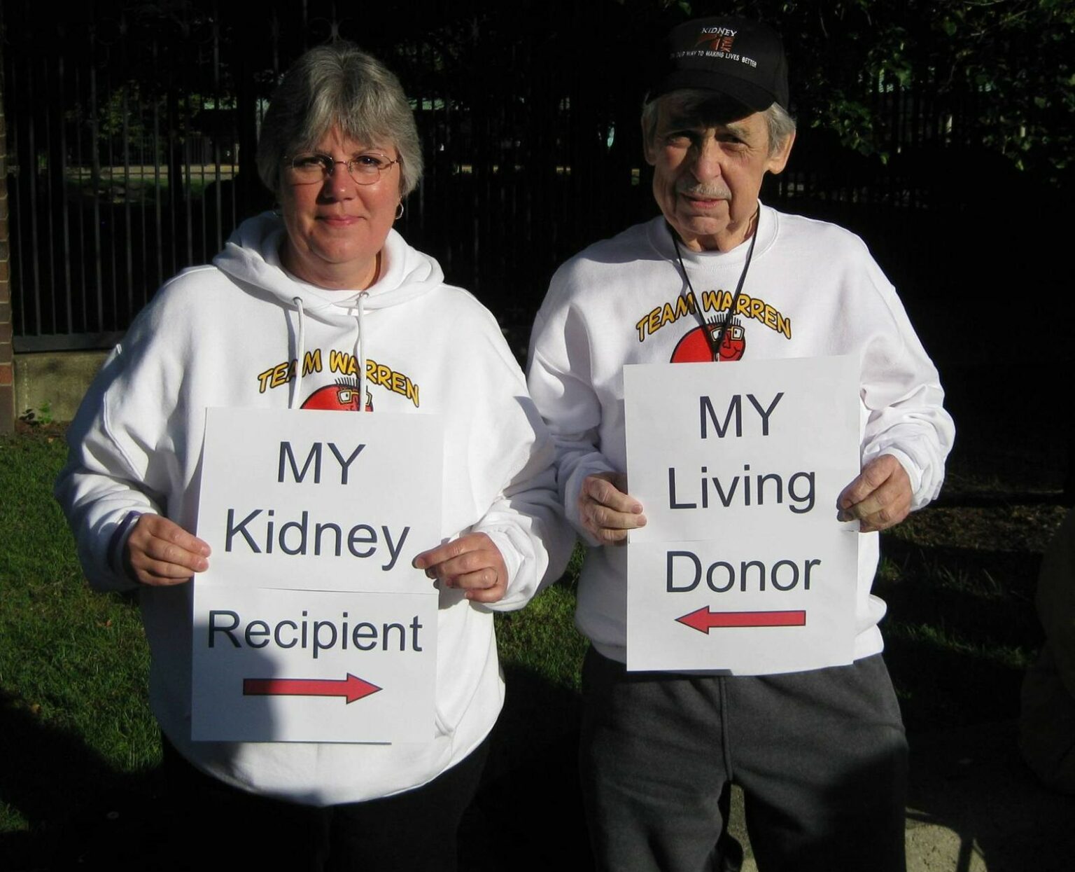 Woman holding sign saying "My Kidney Recipient" with arrow pointing at man, who is holding sign with arrow pointing at her saying "My Living Donor"
