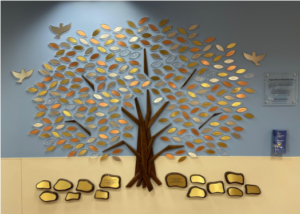 Gold-tone leaves on a tree display on a hospital wall
