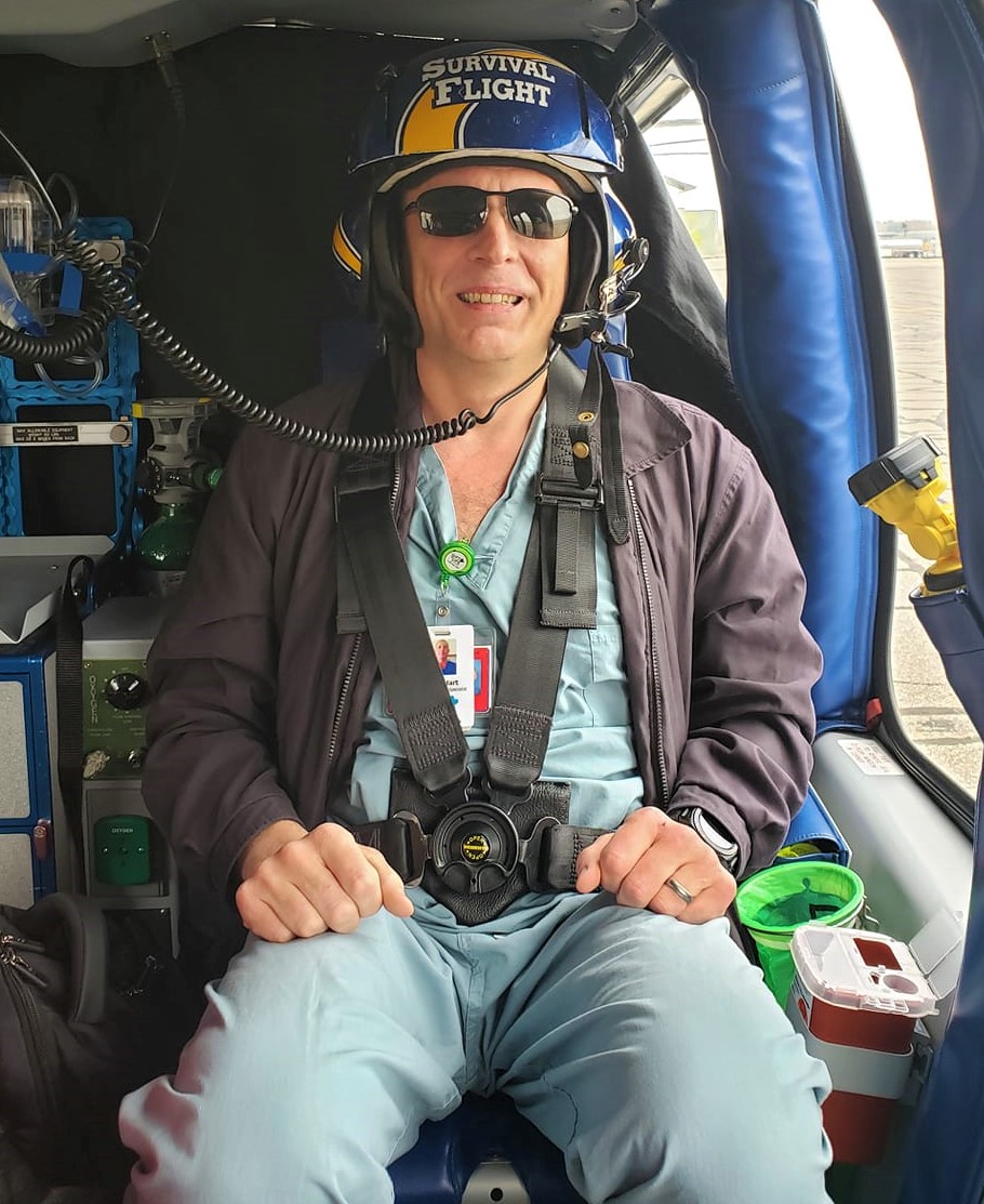 Todd Hart in scrubs sitting in a survival flight helicopter