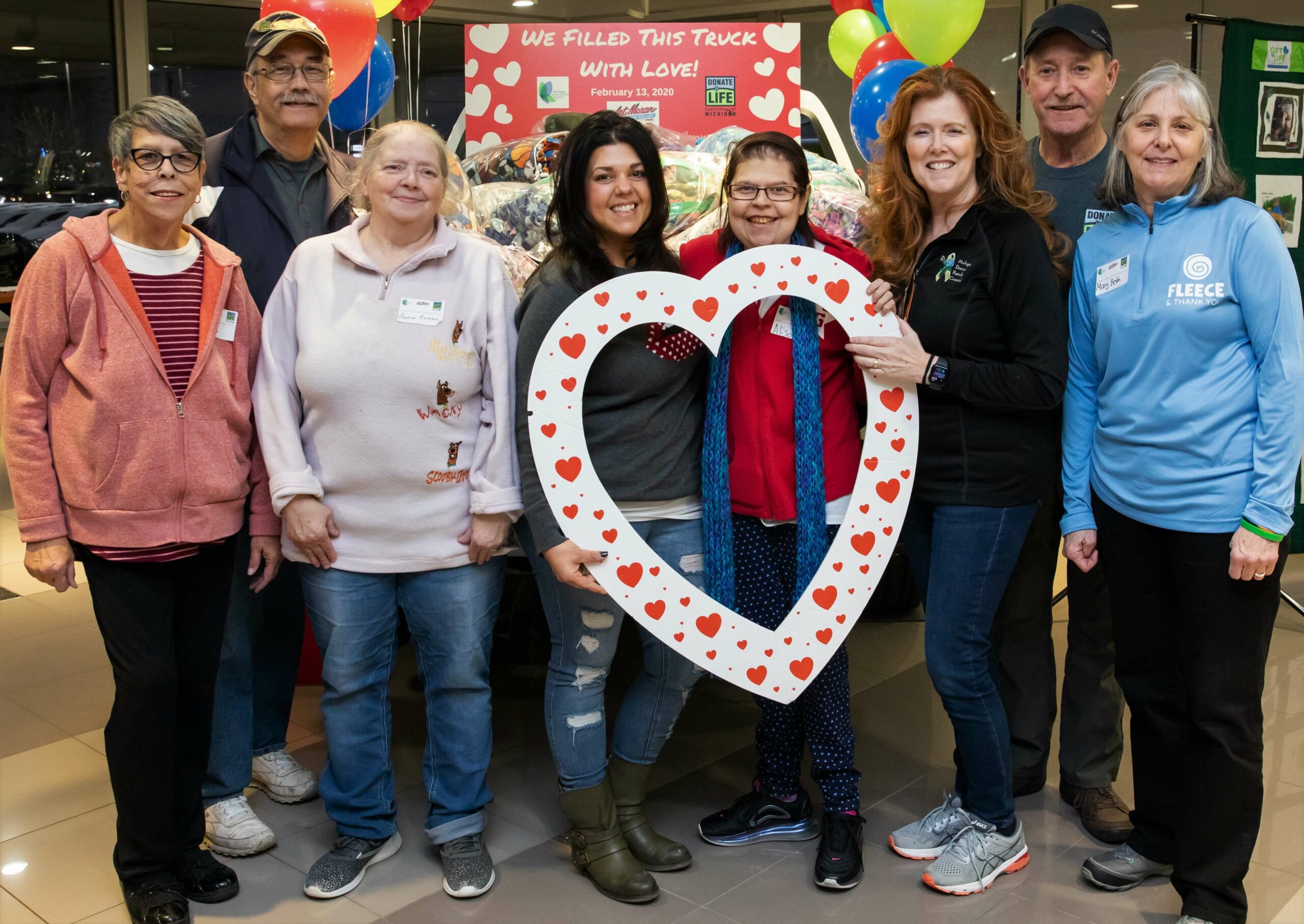 A group of people gathers in front of a truck full of comfort blankets