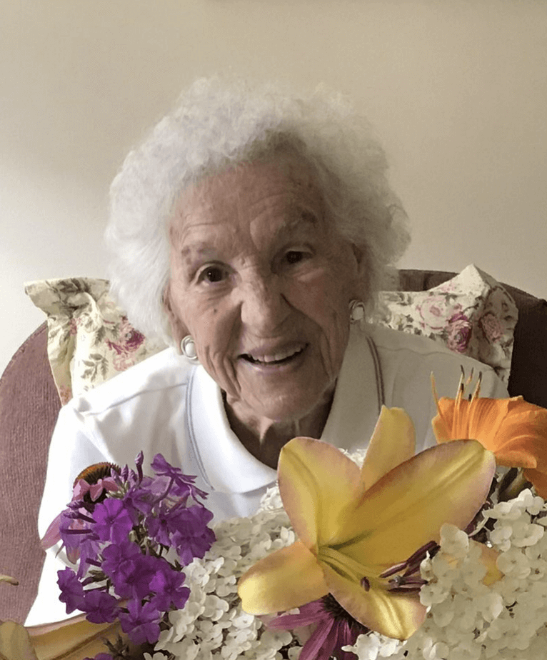 Elderly woman smiling at the camera from behind a large bouquet of flowers