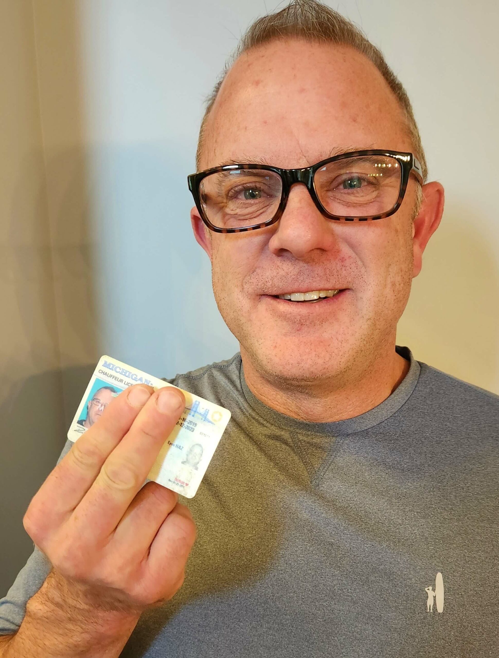 White man holding up his driver's license, showing donor heart symbol