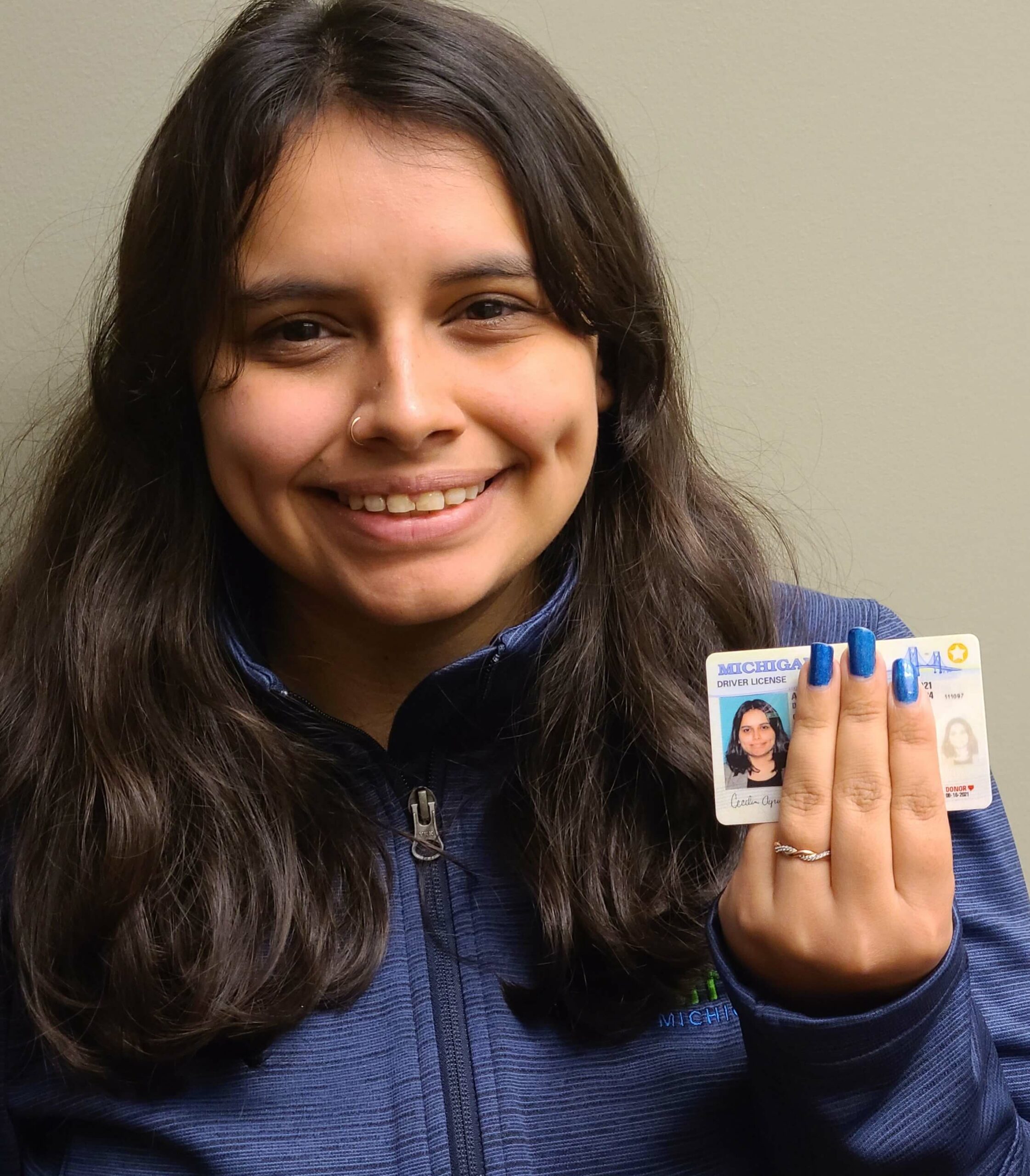 Latina woman holding up driver's license, showing the donor heart symbol