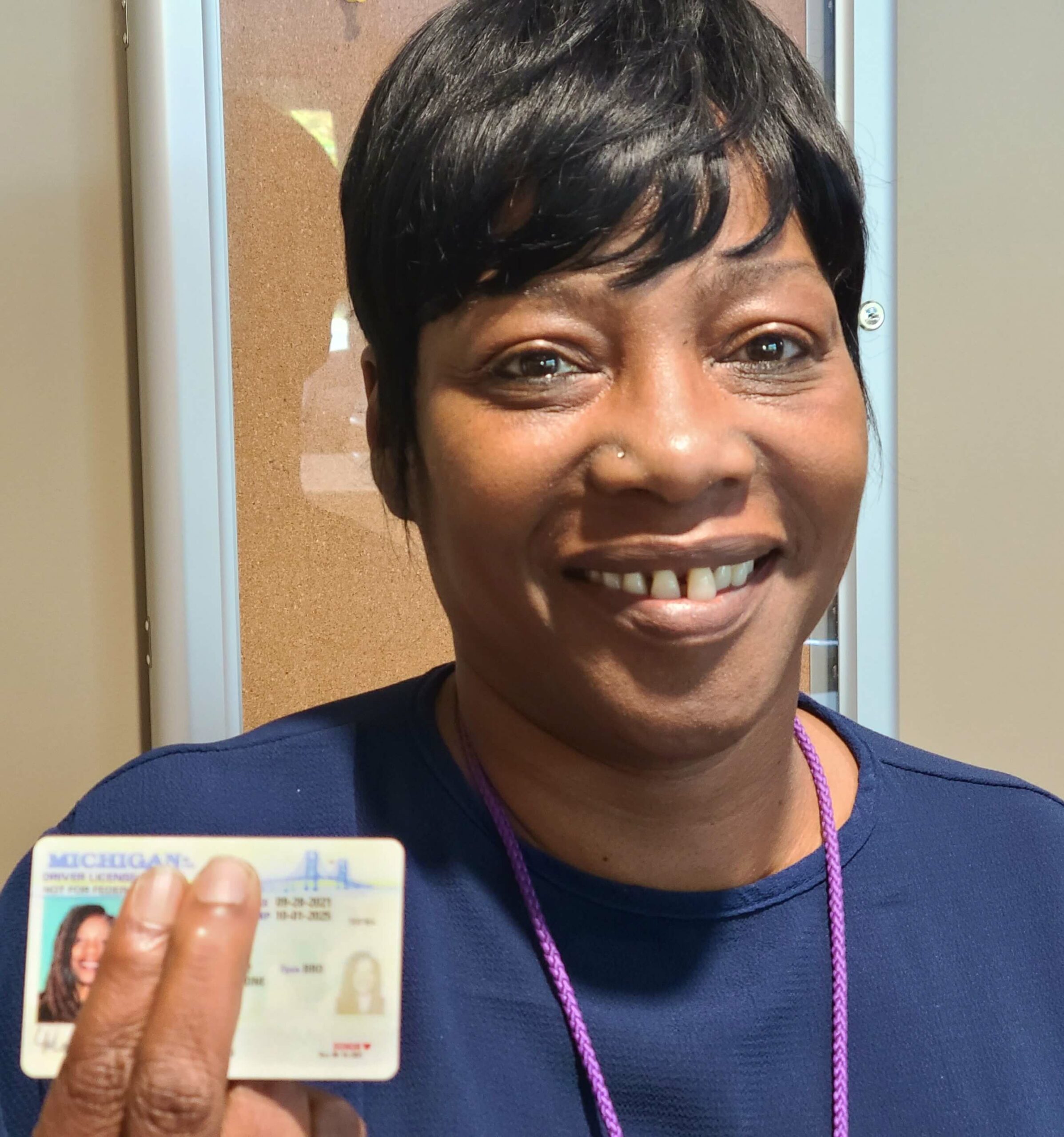 Black woman holding up driver's license, showing donor heart symbol