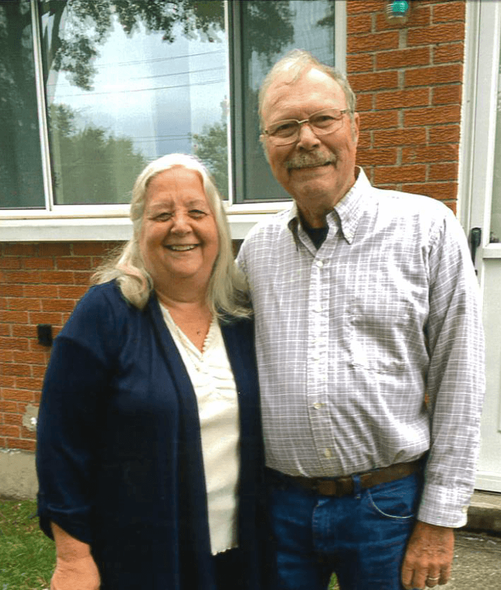 Older couple standing in front of their house, arm in arm