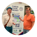 Lansing City Clerk and Deputy Clerk in front of a Check Your Heart banner