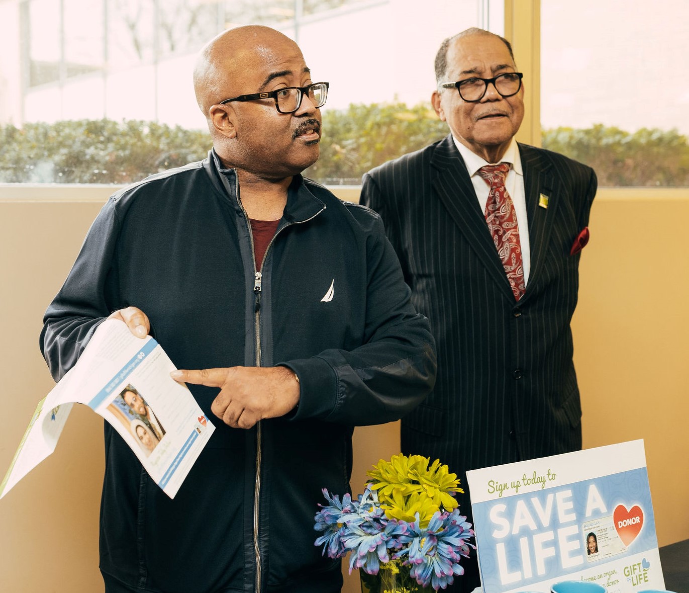 Two Black men at an information table sharing facts about organ donation