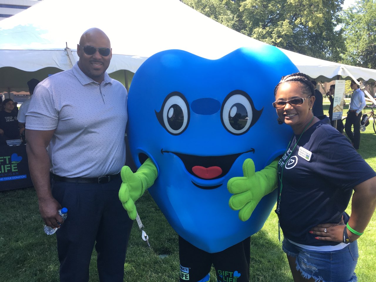 Mayor Ron Bacon, Hartley T. Heart (giant blue heart mascot) and Amy Bacon (heart transplant recipient) outdoors at the Capitol Rally in 2022.