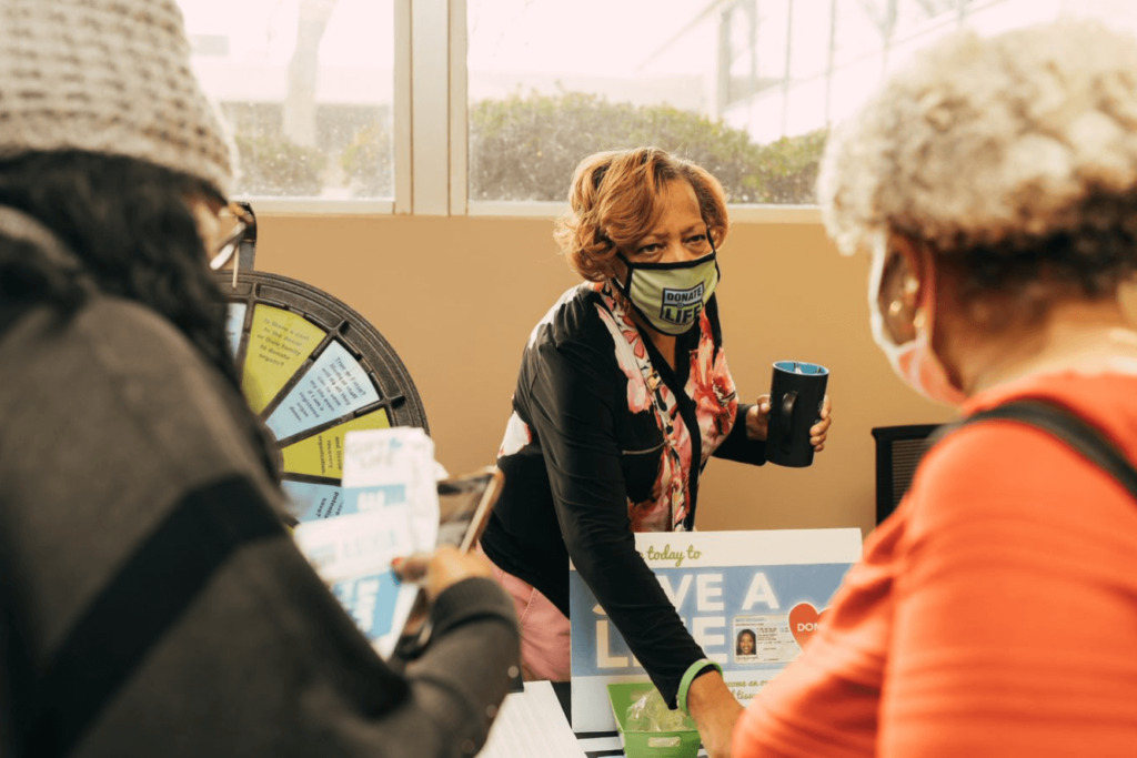 Aarolyn McCullough, wearing a mask during the covid pandemic, provides information to guests at an info table.