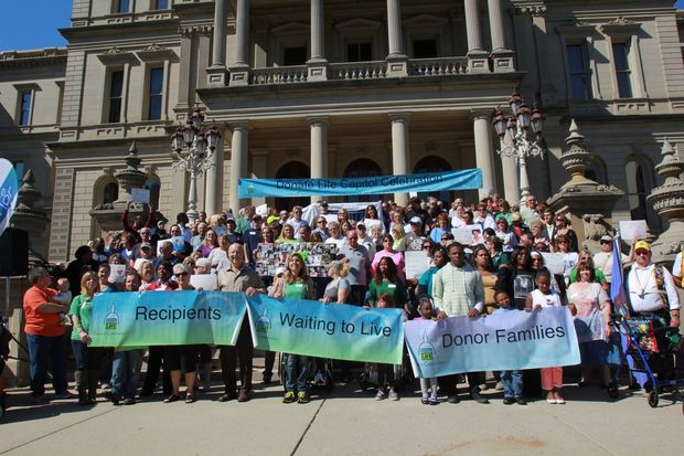 A large group gathered on the Michigan Capitol steps holding signs recognizing them as donor families, transplant recipients and those waiting to live.