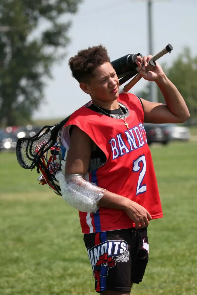 Tristan Johnson walking across the lacrosse field carrying his game gear