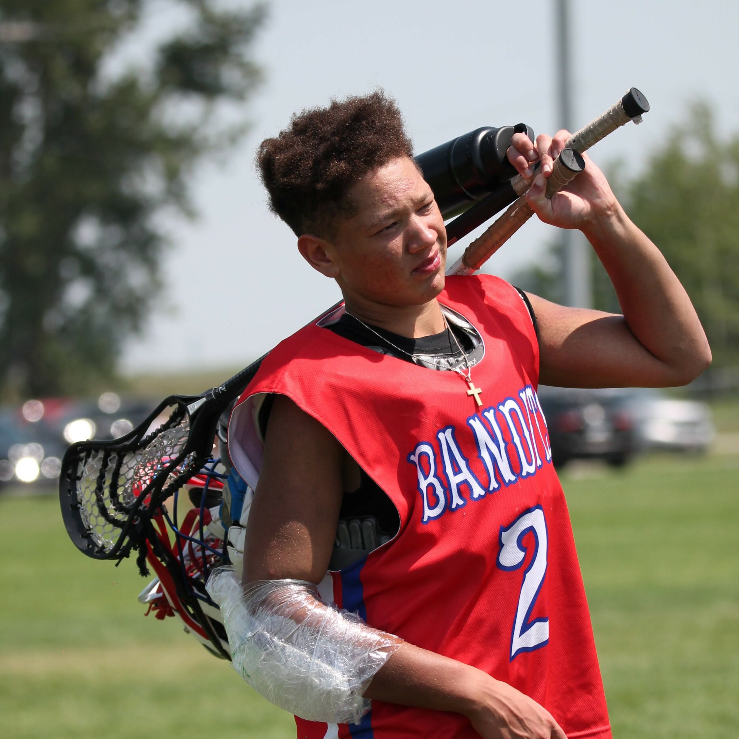 Tristan Johnson in his Bandits lacrosse uniform carrying his gear