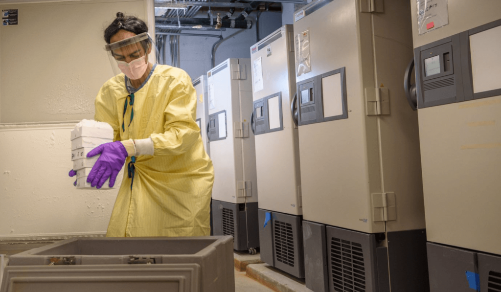 A researcher at the Leiber Institute carries a container near tall coolers