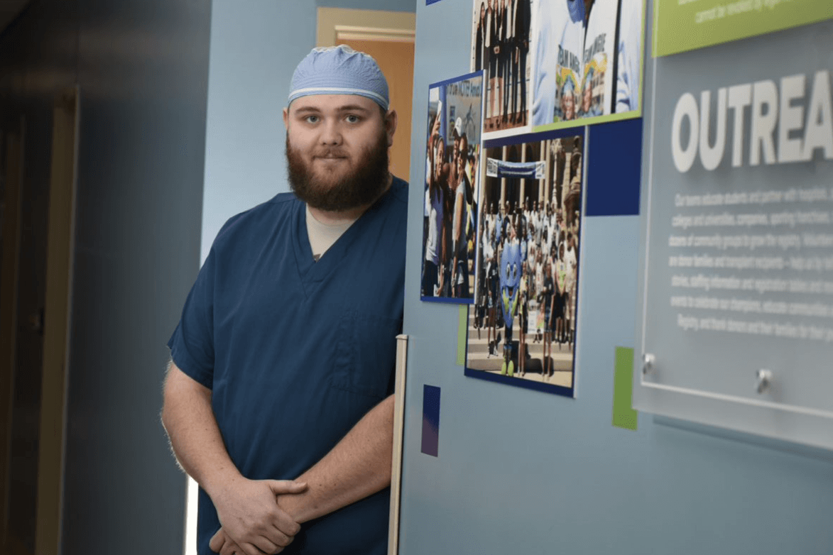 Nick Olden in scrubs next to the Donor Care Center mural at Gift of Life Michigan
