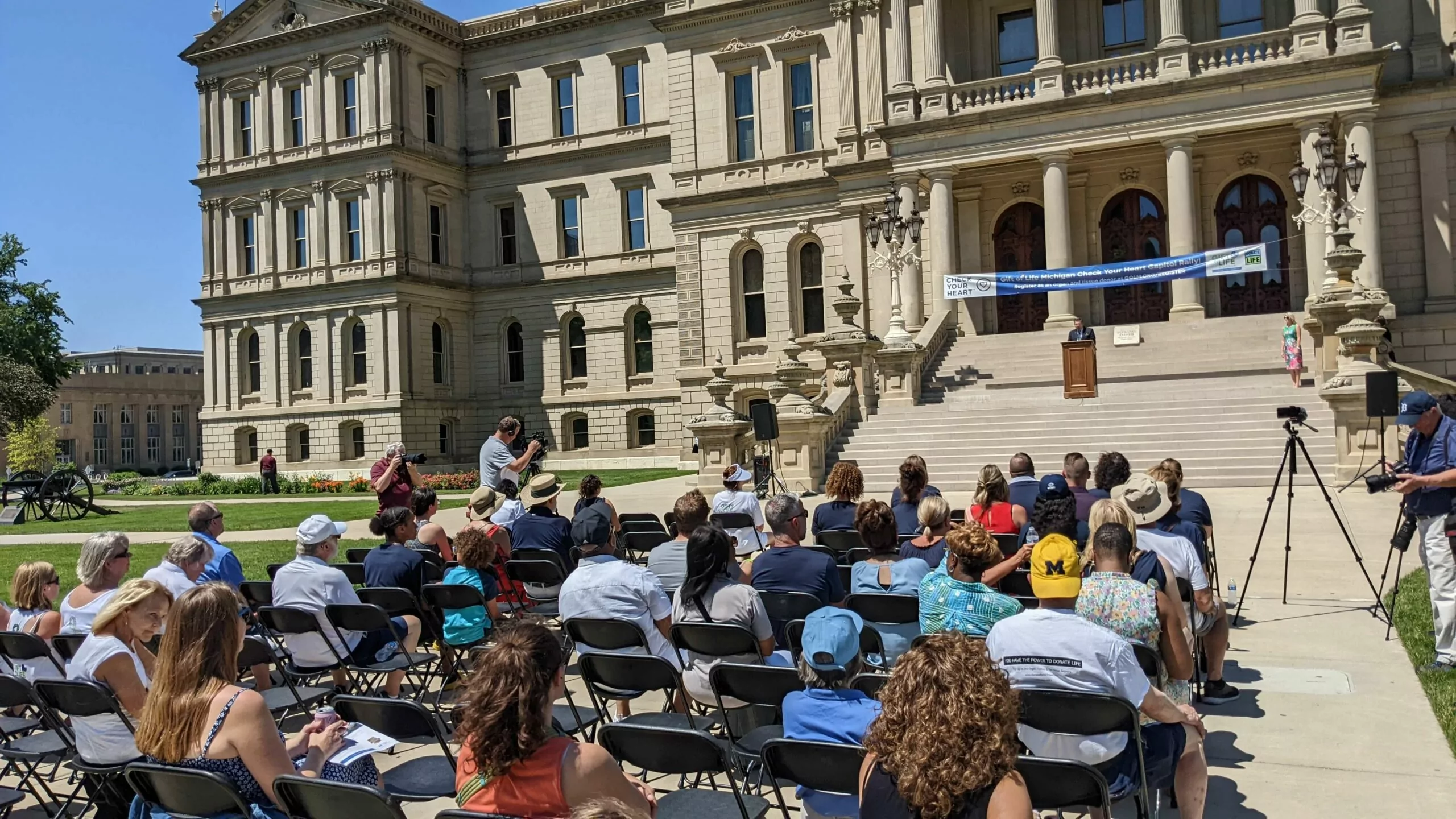 A crowd seated in front of the Michigan Capitol Building steps during the Check Your Heart Capitol Rally