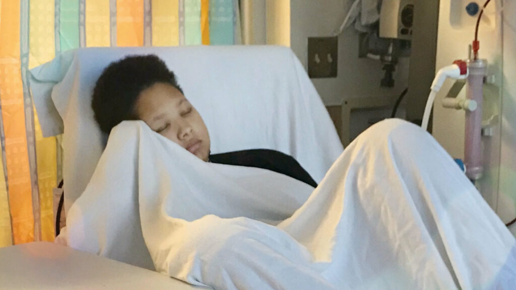 Tristan Johnson catches a nap under a blanket while getting a dialysis treatment.