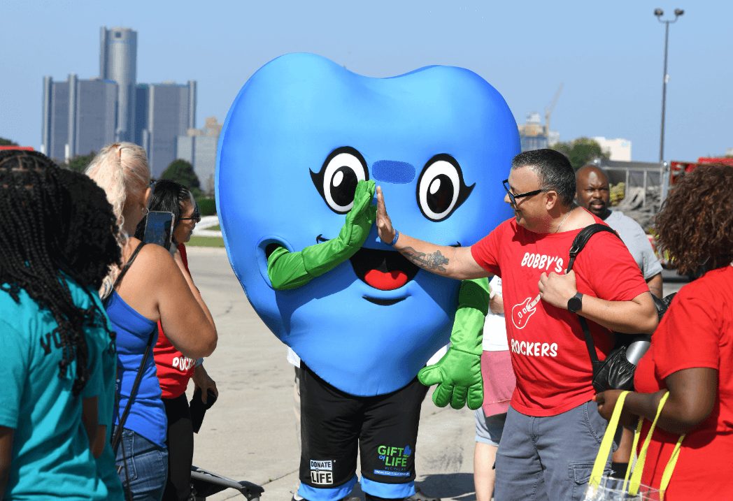 Hartley, the Gift of Life Michigan mascot, gives a high five to a member of Bobby's Rockers at the finish line at LIFE Walk/Run 2023.