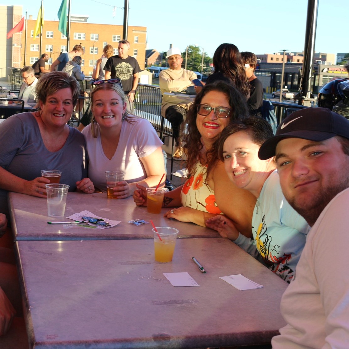 A small group gathered around an outdoor dining table playing trivia