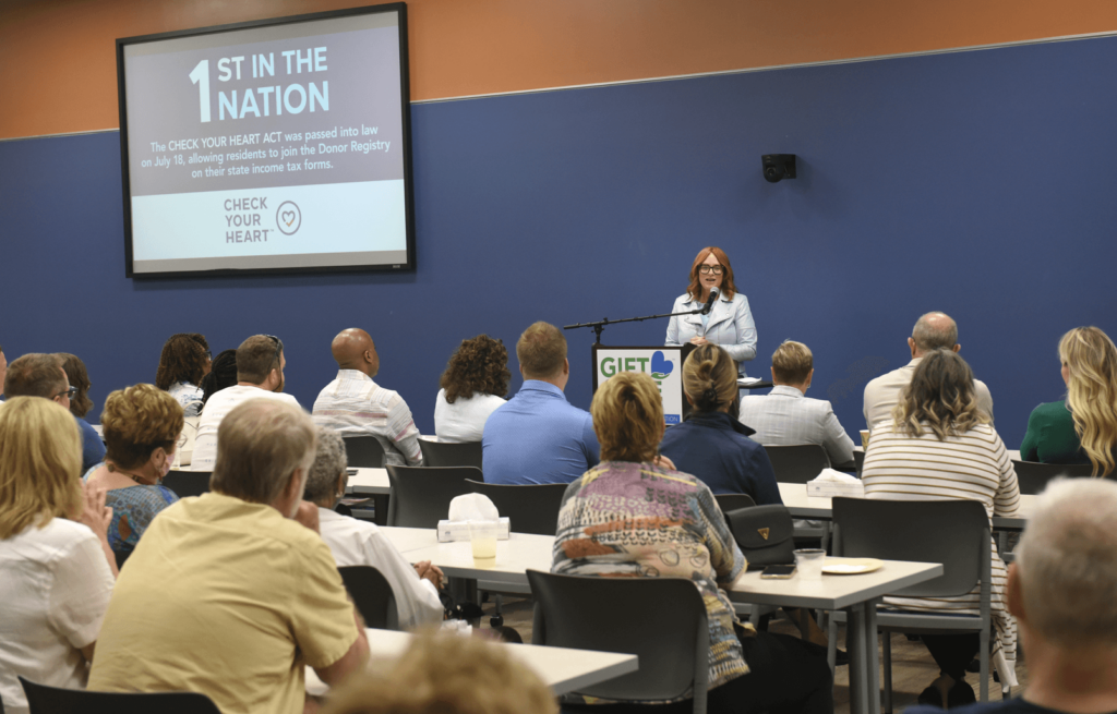 President & CEO Dorrie Dils at the podium in a packed conference center