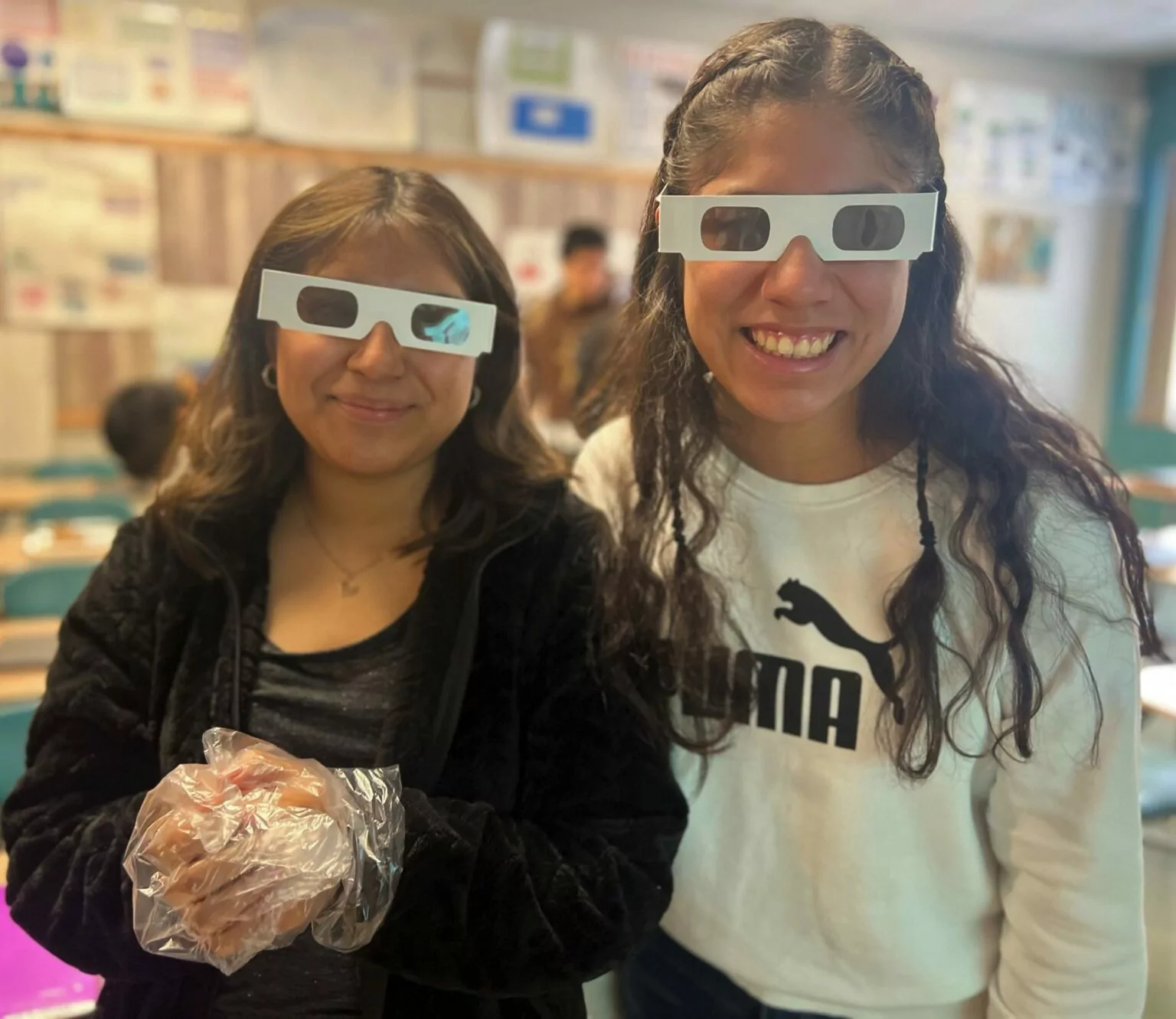 Two teenage girls wearing "cornea glasses" that distort vision.