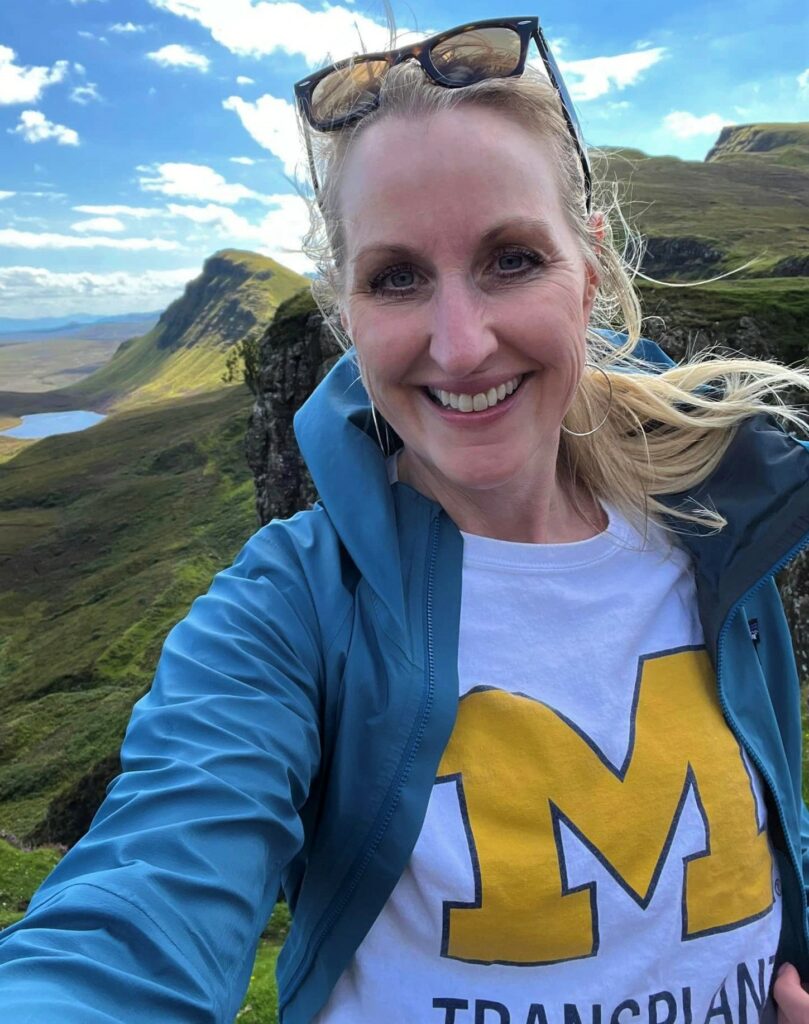 Rachel Kuntzsch in an open field in Scotland, wearing a U of M t-shirt
