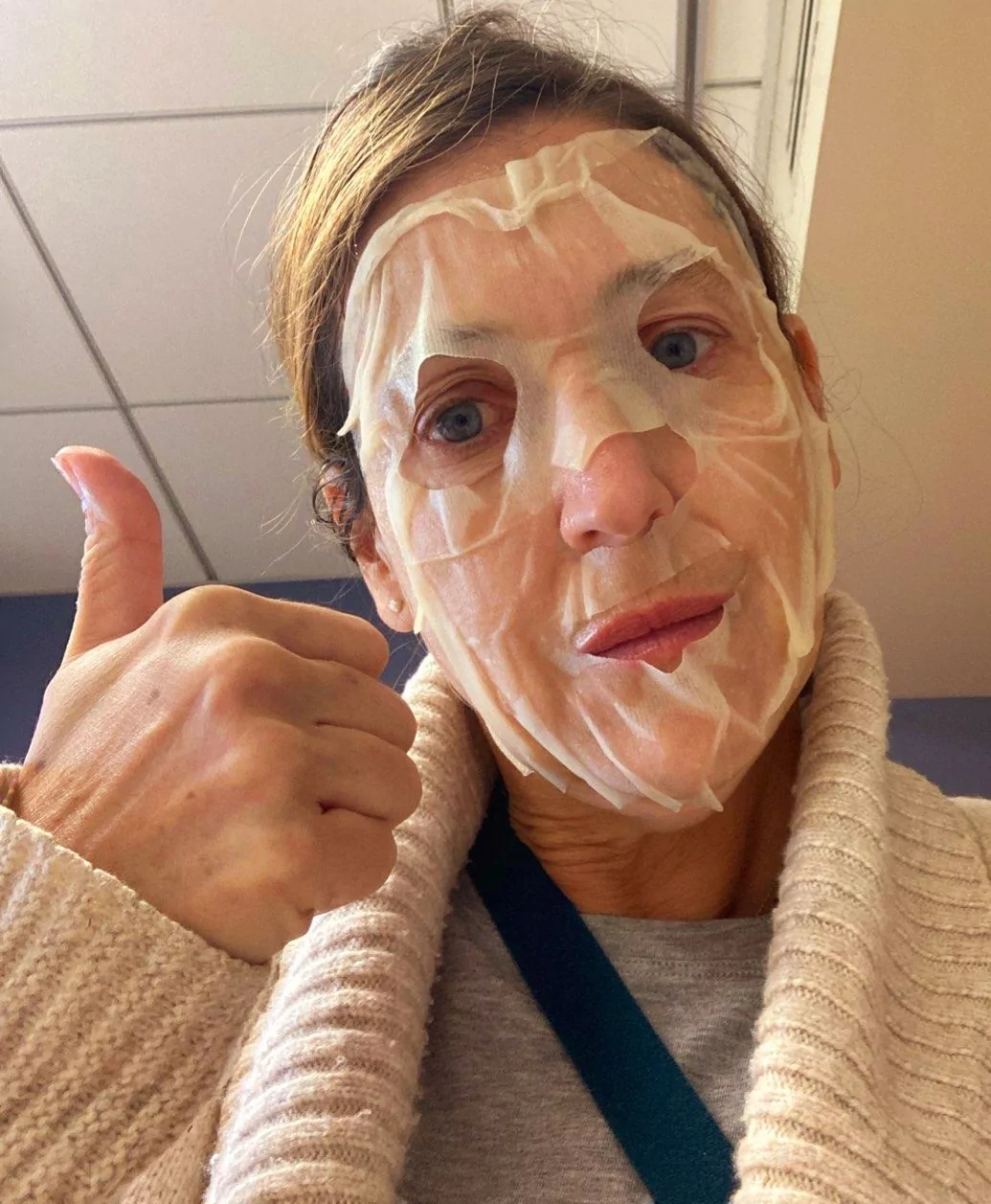 Sherry wearing a facial mask and giving a thumb's up.