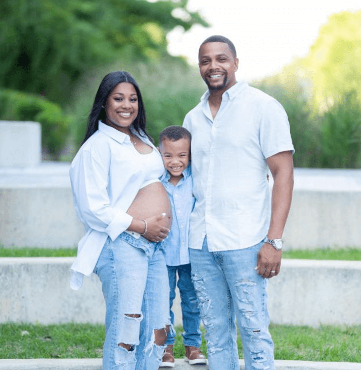 A pregnant woman and a man and their toddler, all wearing white and denim