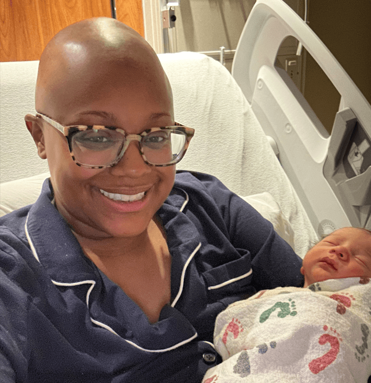 A bald woman in a hospital bed with a newborn baby