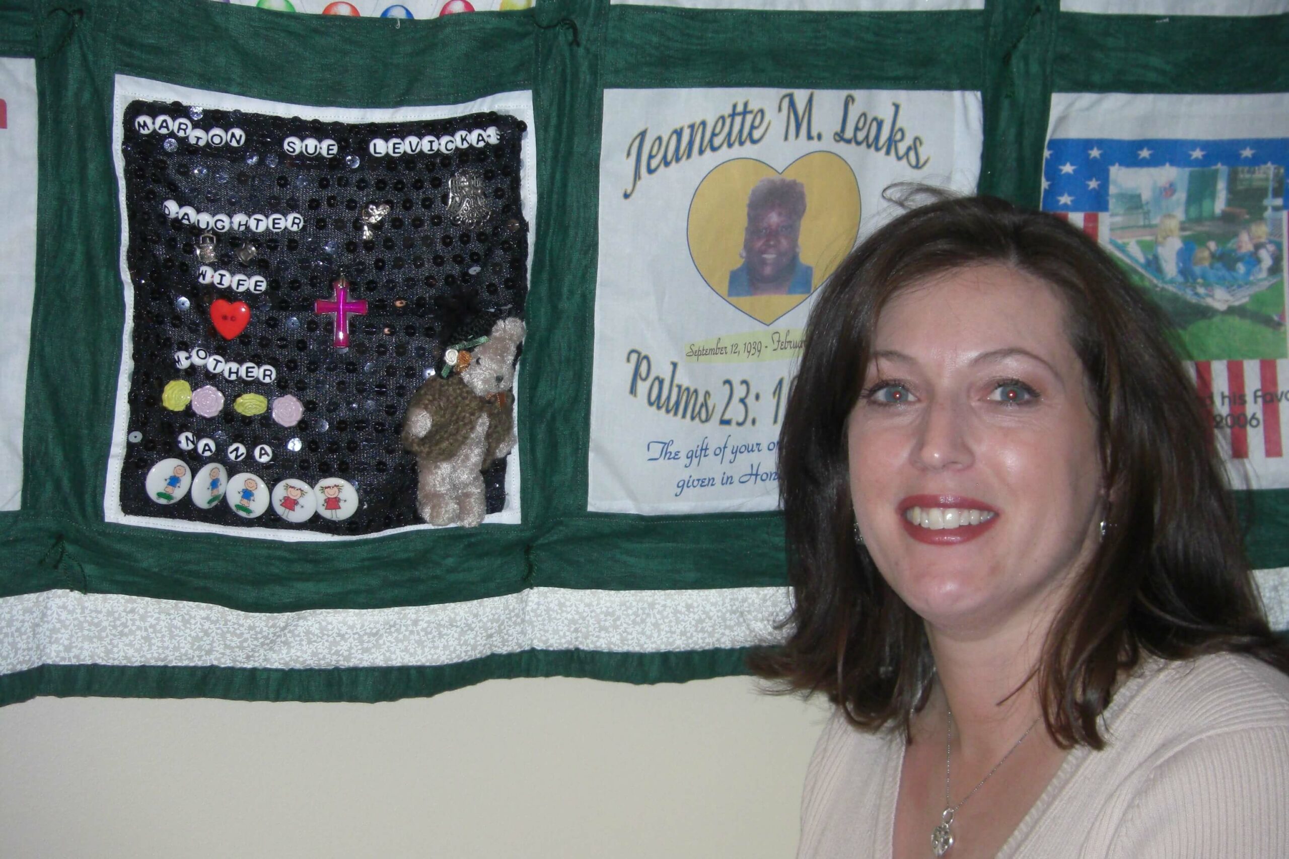 Sherry Johnson next to her donor Sue's quilt square on a Memories From Michigan Donor Quilt
