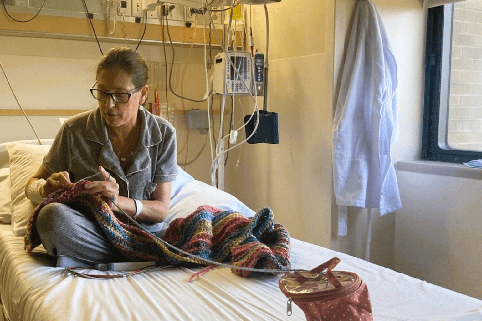 Sherry Johnson sits on her hospital bed, crocheting.