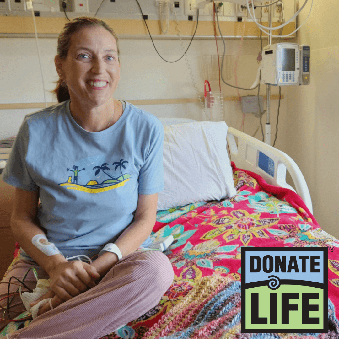 Sherry Johnson sits on her hospital bed at Michigan Medicine, with a big smile. The Donate Life logo is in the corner of the photo.