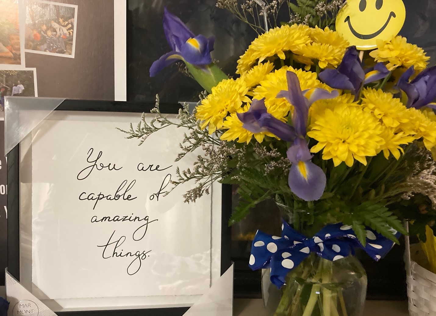 A vase of yellow daisy-like flowers and a note that says "You are capable of amazing things."
