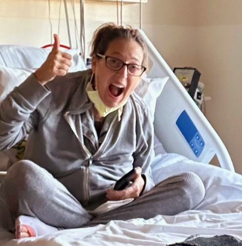 Sherry Johnson sits cross-legged in her street clothes on her hospital bed while recovering from her heart/kidney transplant.