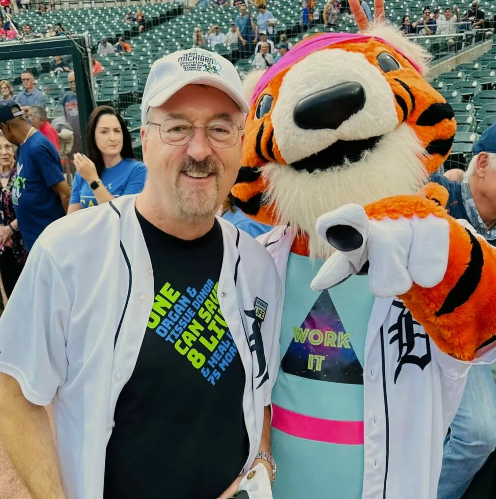 Chris Kowalski with mascot Paws at a Detroit Tigers game this summer. He talked with high school students about donation by live video from Comerica Park that night.