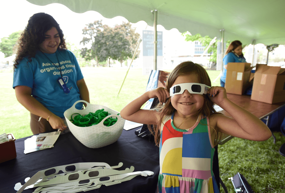 A young girl tries on a pair of glasses that simulate needing a cornea transplant at the 2024 Check Your Heart Capitol Rally