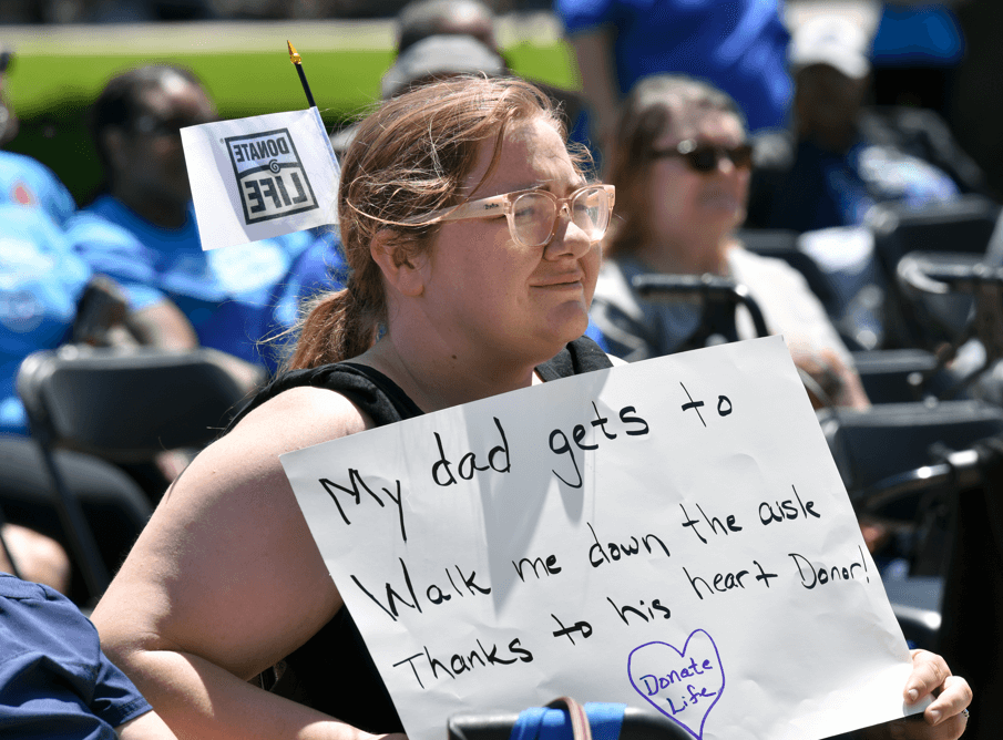 A woman holds a sign about her father's heart transplant at the 2024 Check Your Heart Capitol Rally