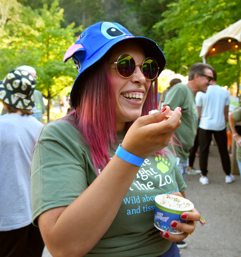 A woman with a fun animal hat enjoys Dippin' Dots at Donate Life Night at the Zoo