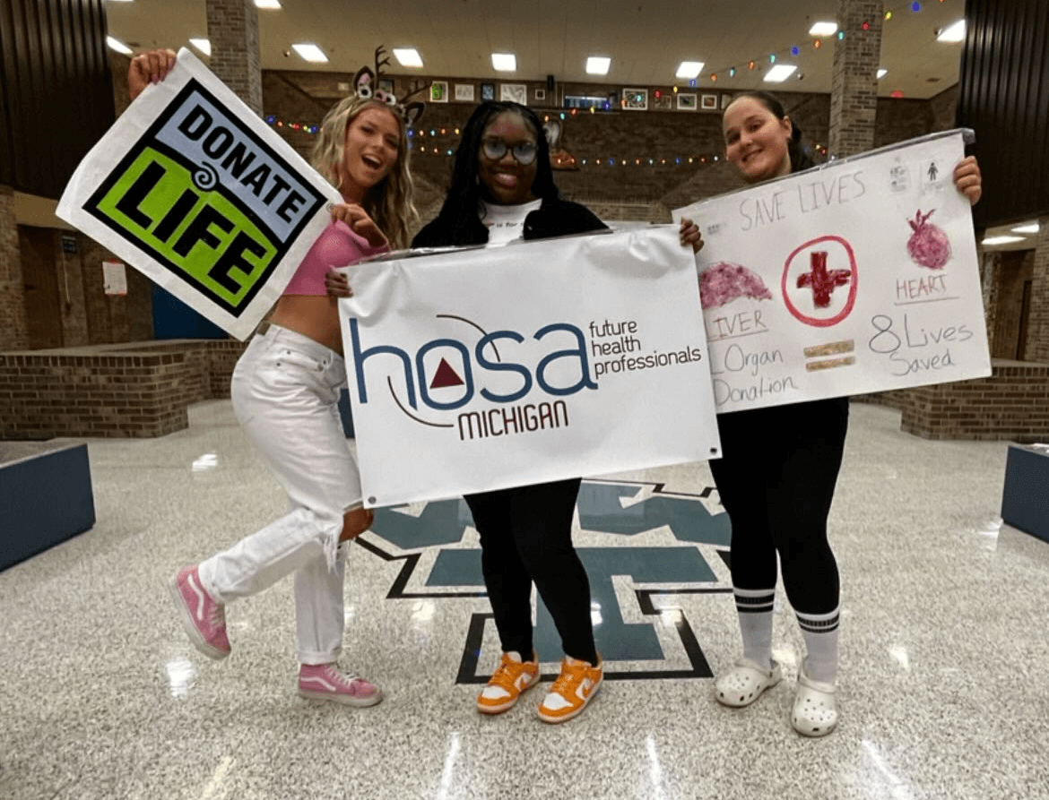 High school students holding up a homepage poster, a HOSA sign and a Donate Life banner