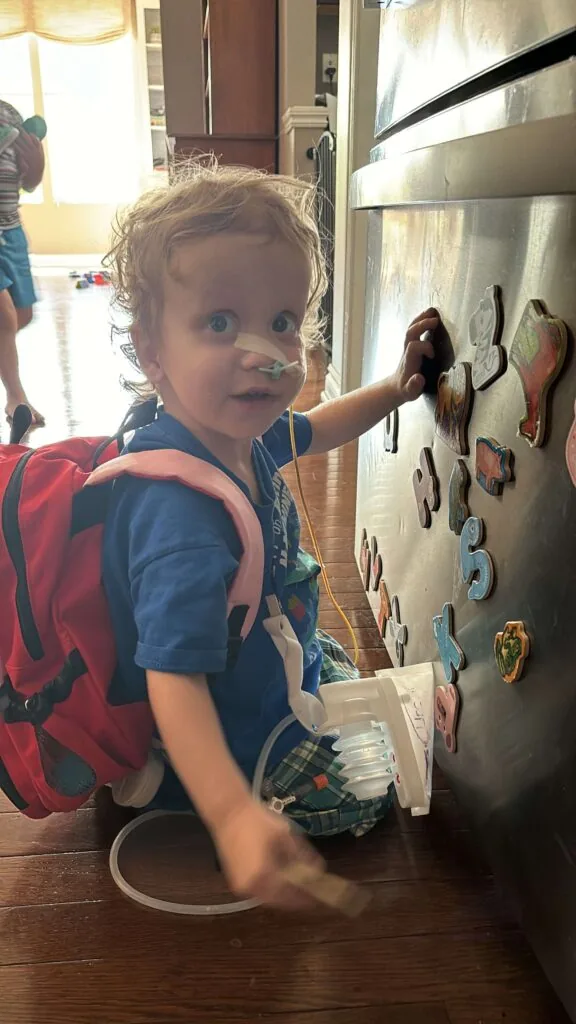 Blake Hermann, liver transplant recipient, playing with foam numbers on a wall.