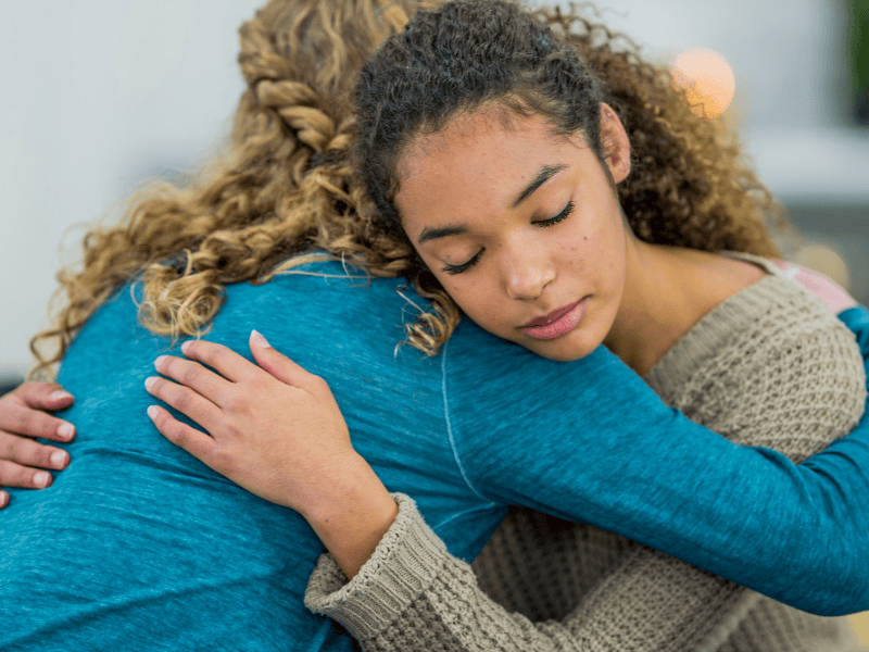 Two women embracing while sad.