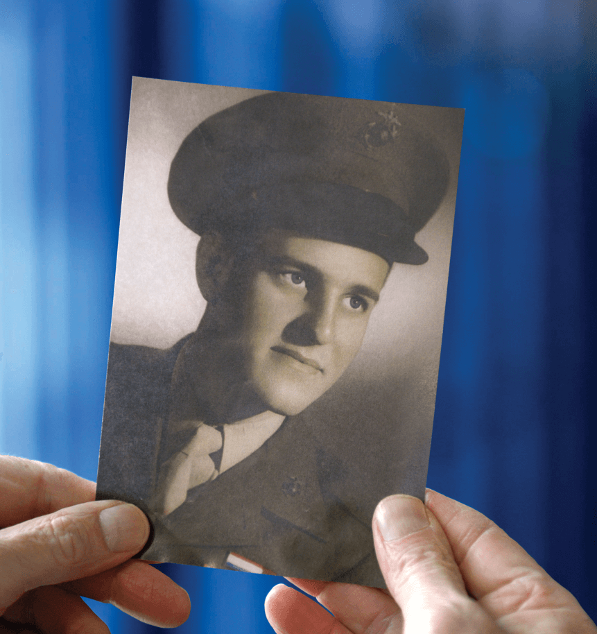 Tim Schramm holding a photo of his father, Ray, in military uniform